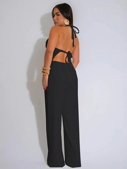 Woman wearing a black open-back jumpsuit on a plain background