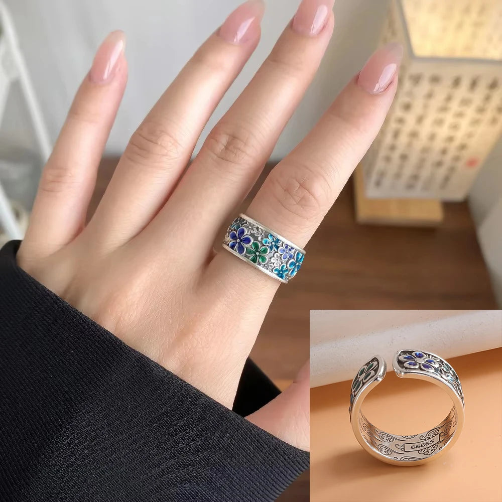 Silver ring with floral design on a finger, close-up view.