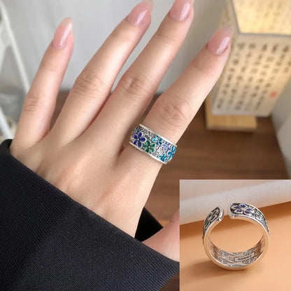 Silver ring with floral design on a finger, close-up view.
