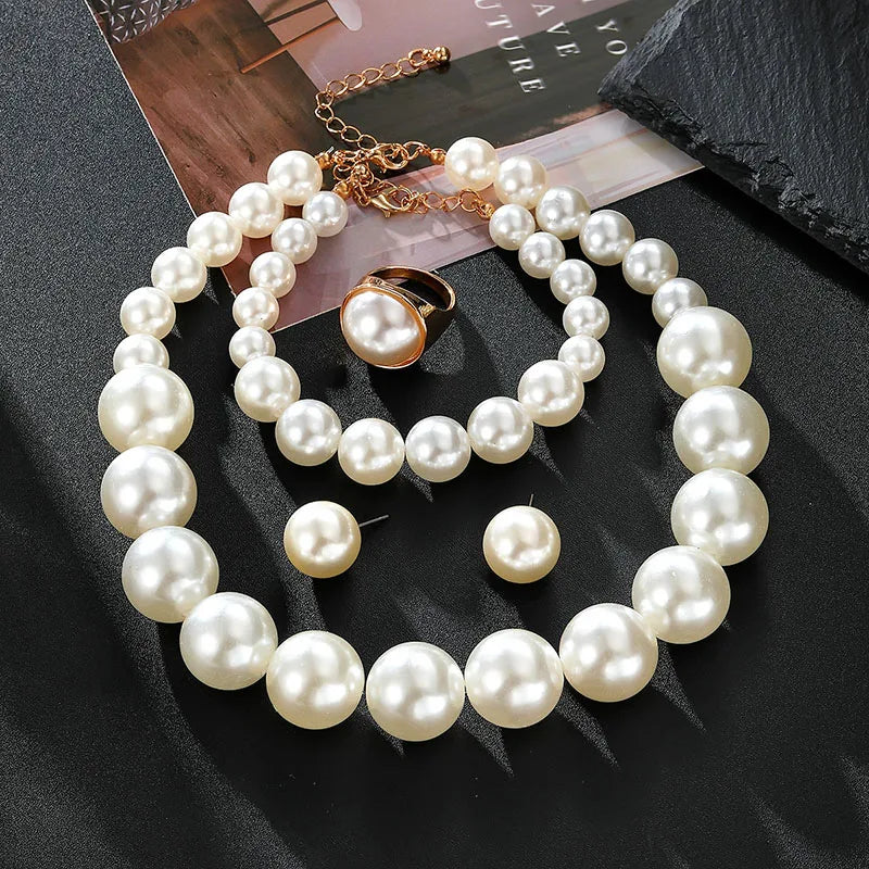 Pearl necklace and earrings on a dark surface with a magazine underneath