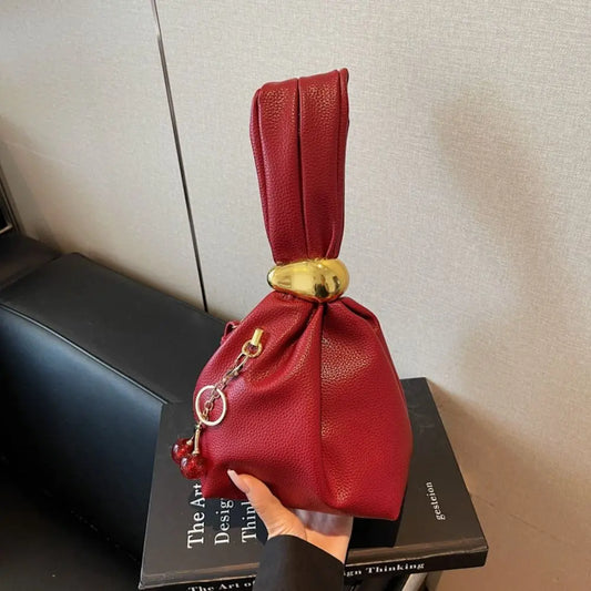 Red drawstring bag with a gold accent on top of a black book