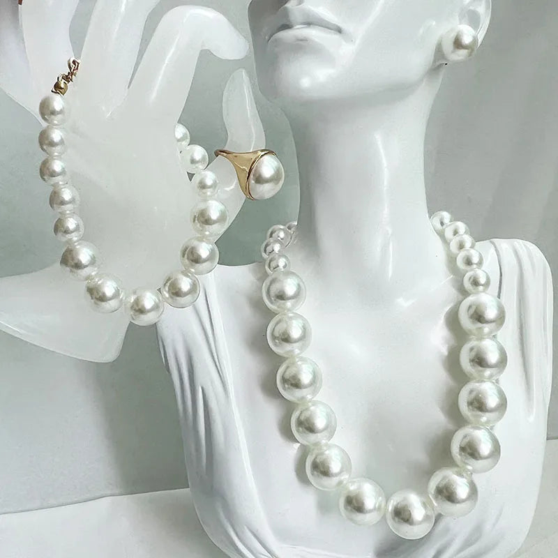 Pearl necklace and earrings on a mannequin bust with a white background