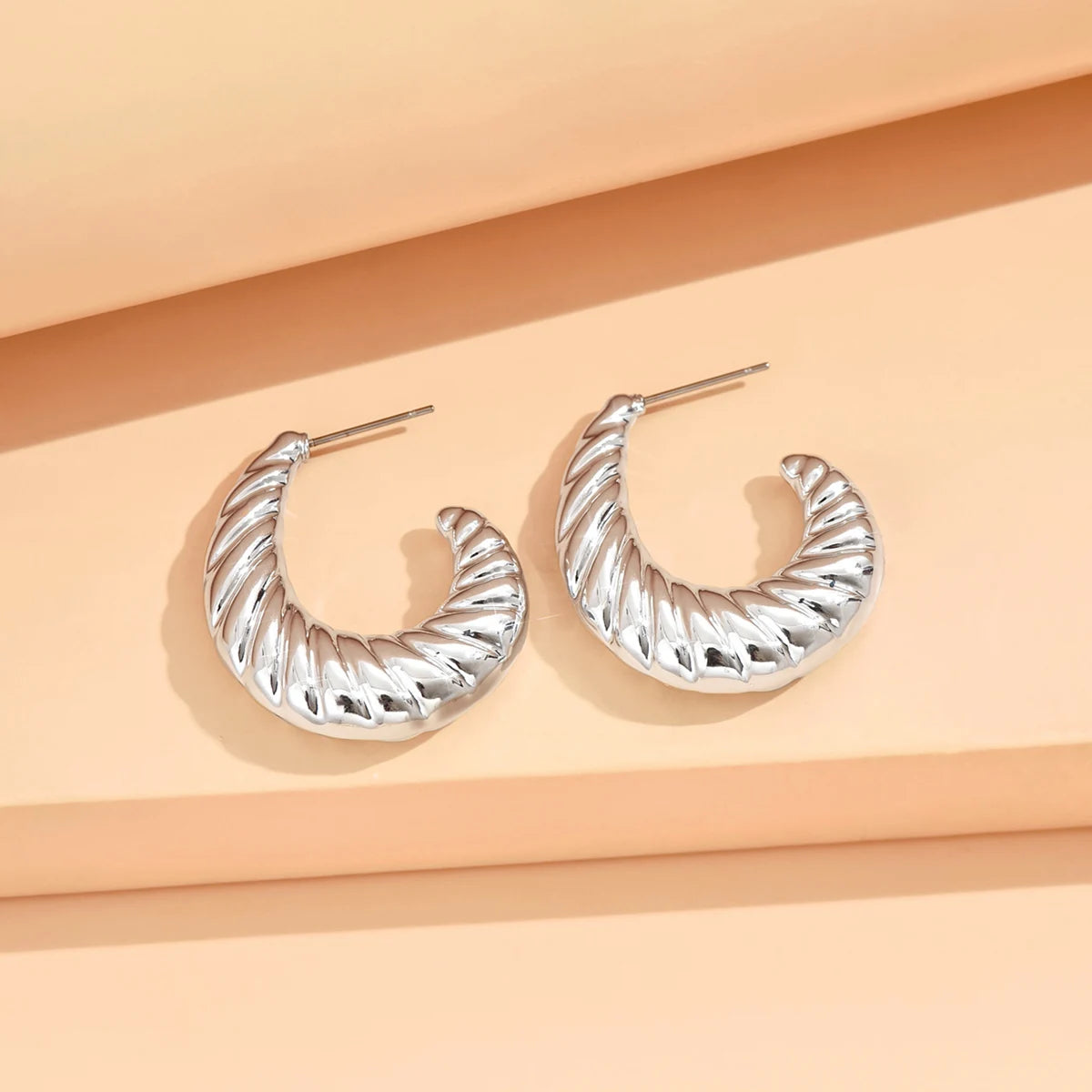 Silver hoop earrings on a peach-colored background