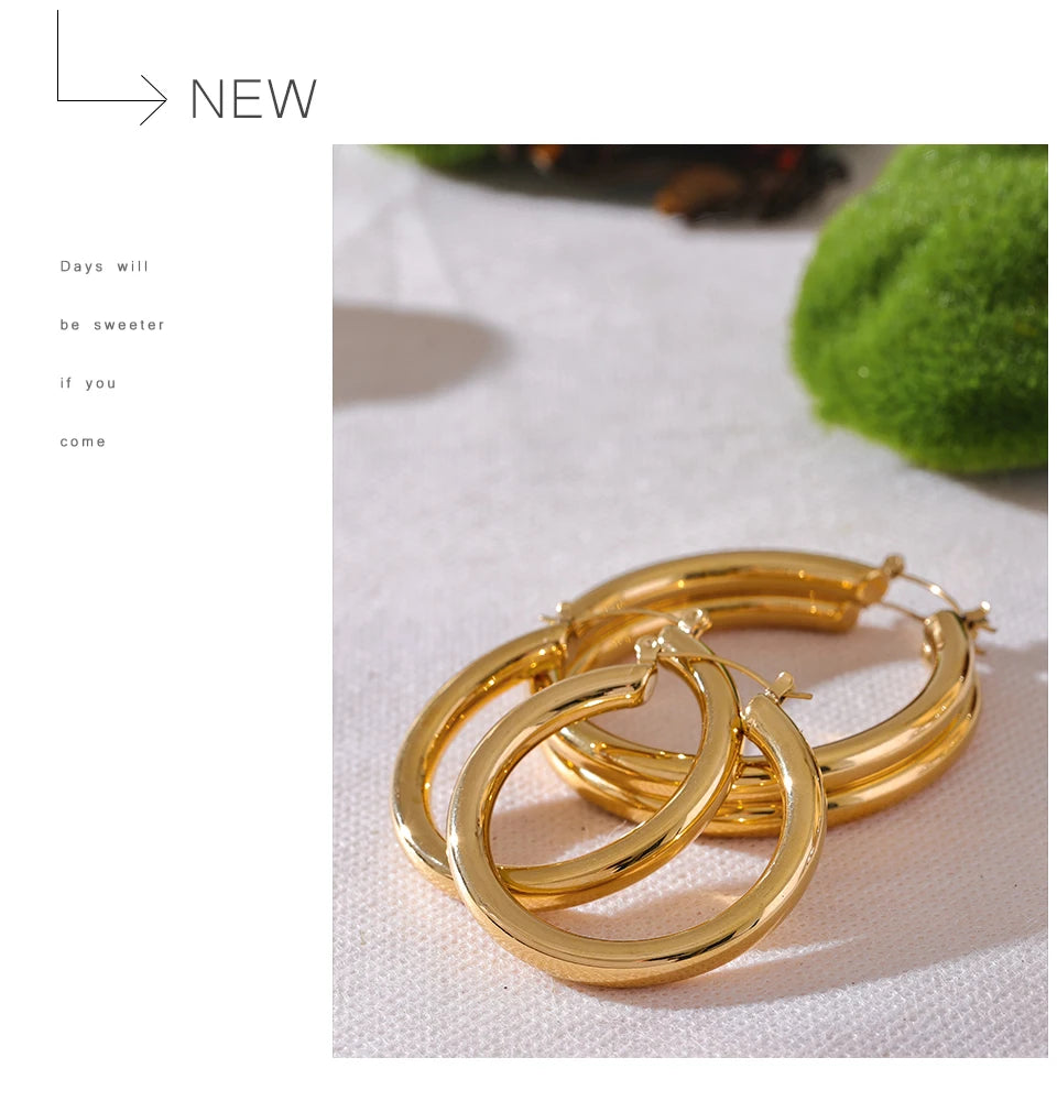 Gold hoop earrings on a light fabric background with text overlay.