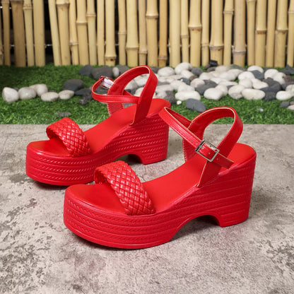 Red platform sandals on a concrete surface with a bamboo and stone background