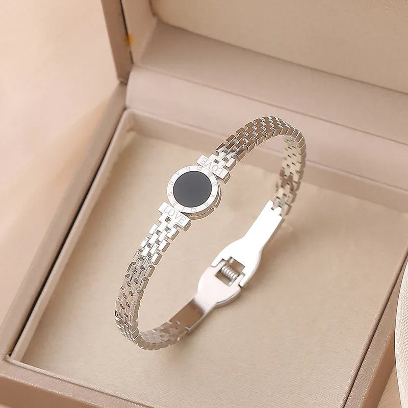 Silver bracelet with a black center stone in an open beige box