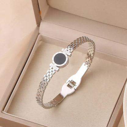 Silver bracelet with a black center stone in an open beige box