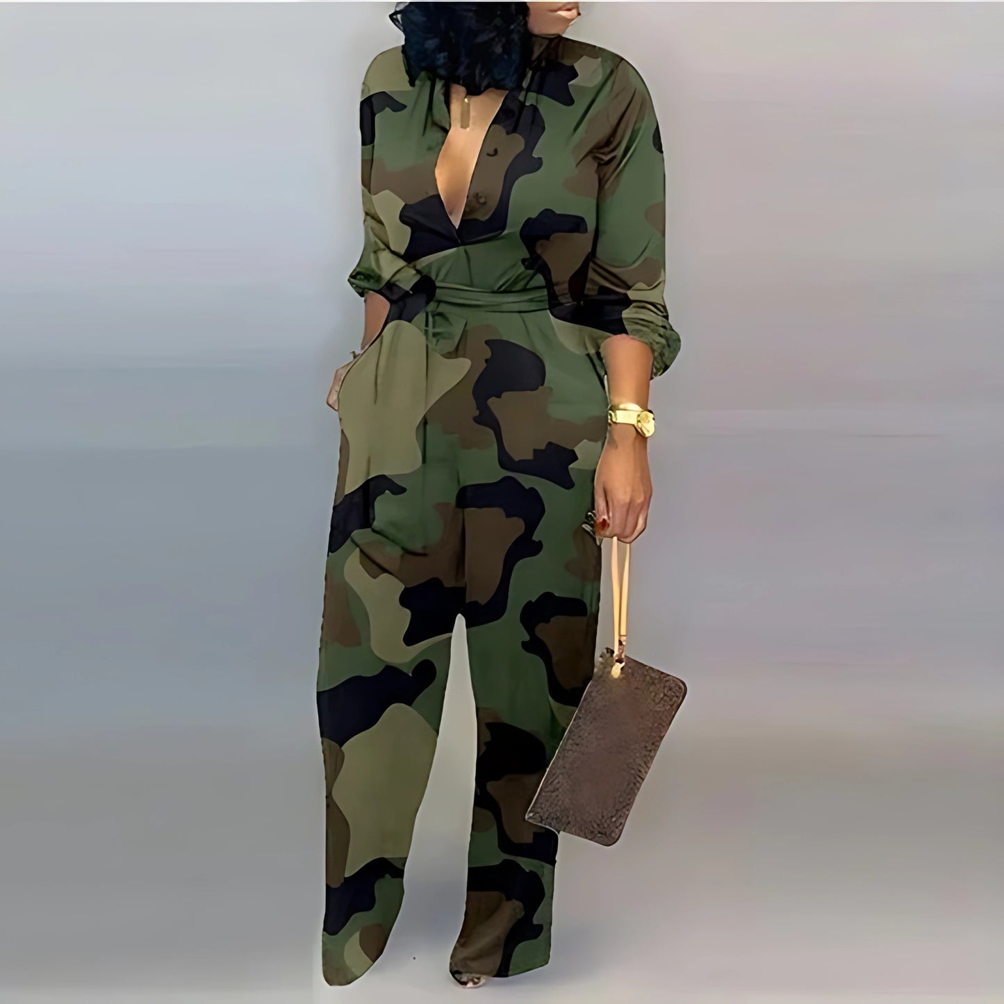 A stylish camouflage-patterned jumpsuit with a plunging neckline and a tied waist. The outfit is complemented by a brown clutch bag, gold jewelry, and reflective heels for a sleek finish.