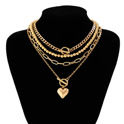 Gold chain necklaces with heart pendants on a black mannequin bust.