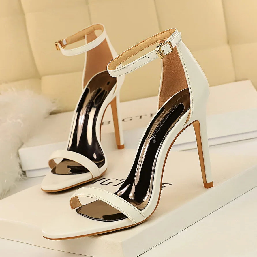 White high-heeled sandals with gold accents on a light background