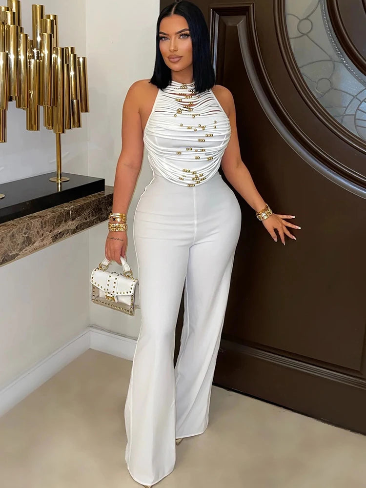 Woman in a white outfit with gold accents standing indoors.