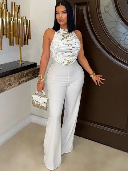 Woman in a white outfit with gold accents standing indoors.