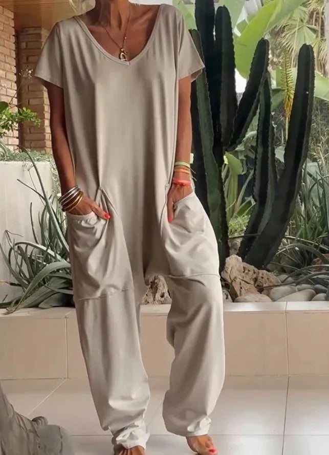 Person wearing a light gray jumpsuit with cacti in the background