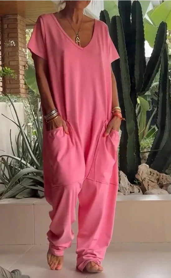 Person wearing a pink outfit standing in a garden with plants and rocks.