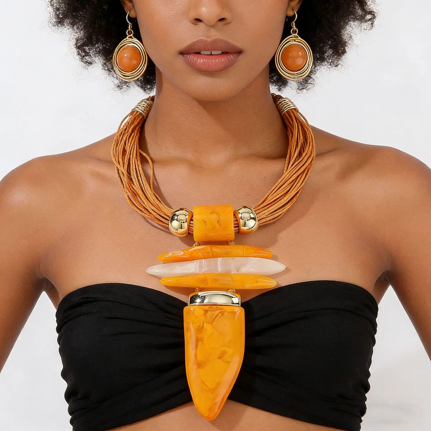Woman wearing an orange and gold necklace and earrings on a white background