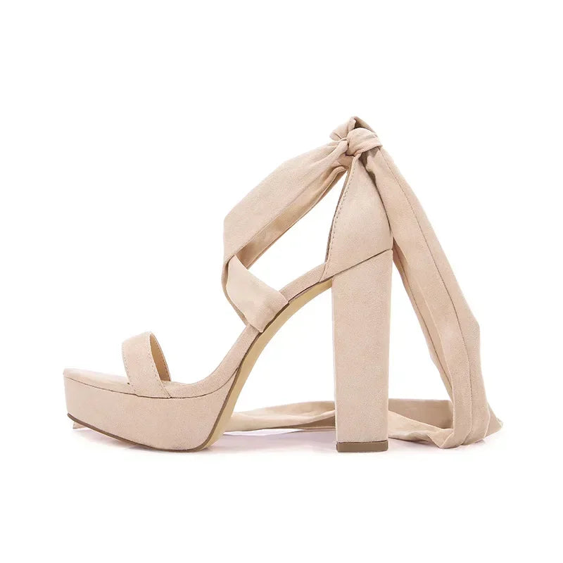 Beige chunky high heel gladiator sandals with lace-up straps.