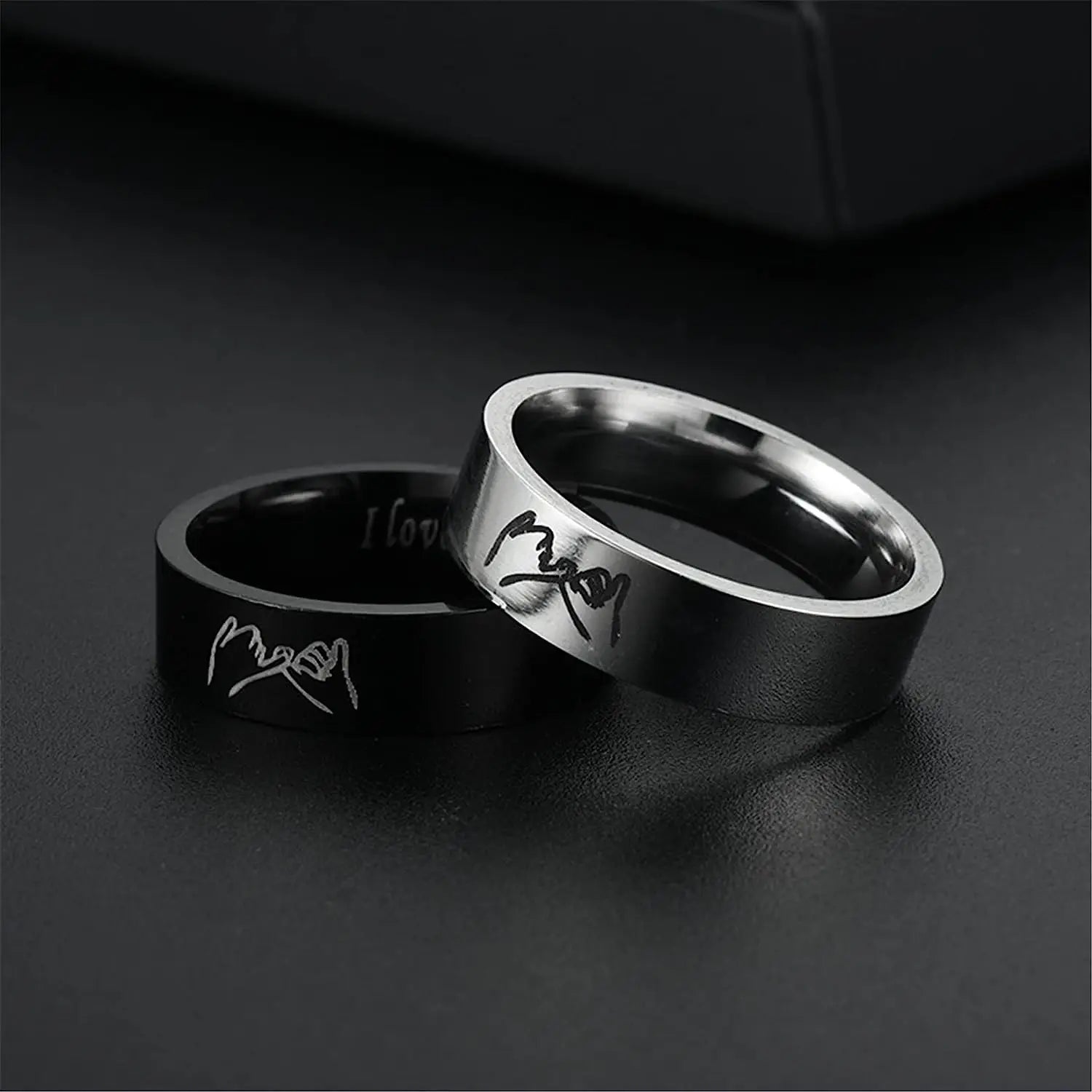 Two rings, one black and one silver, on a dark surface