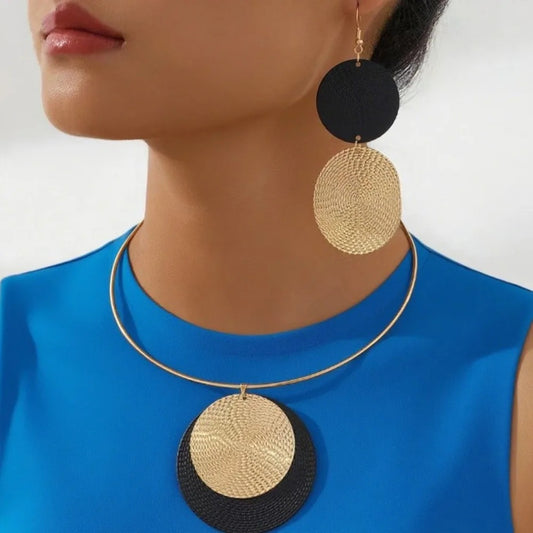 Close-up of a person wearing a gold and black circular earring and necklace.