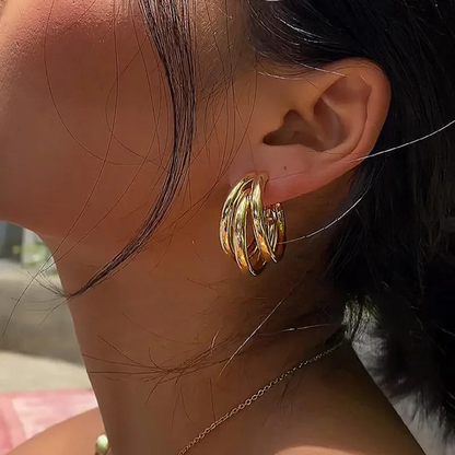 Close-up of a person wearing a gold hoop earring with a blurred background