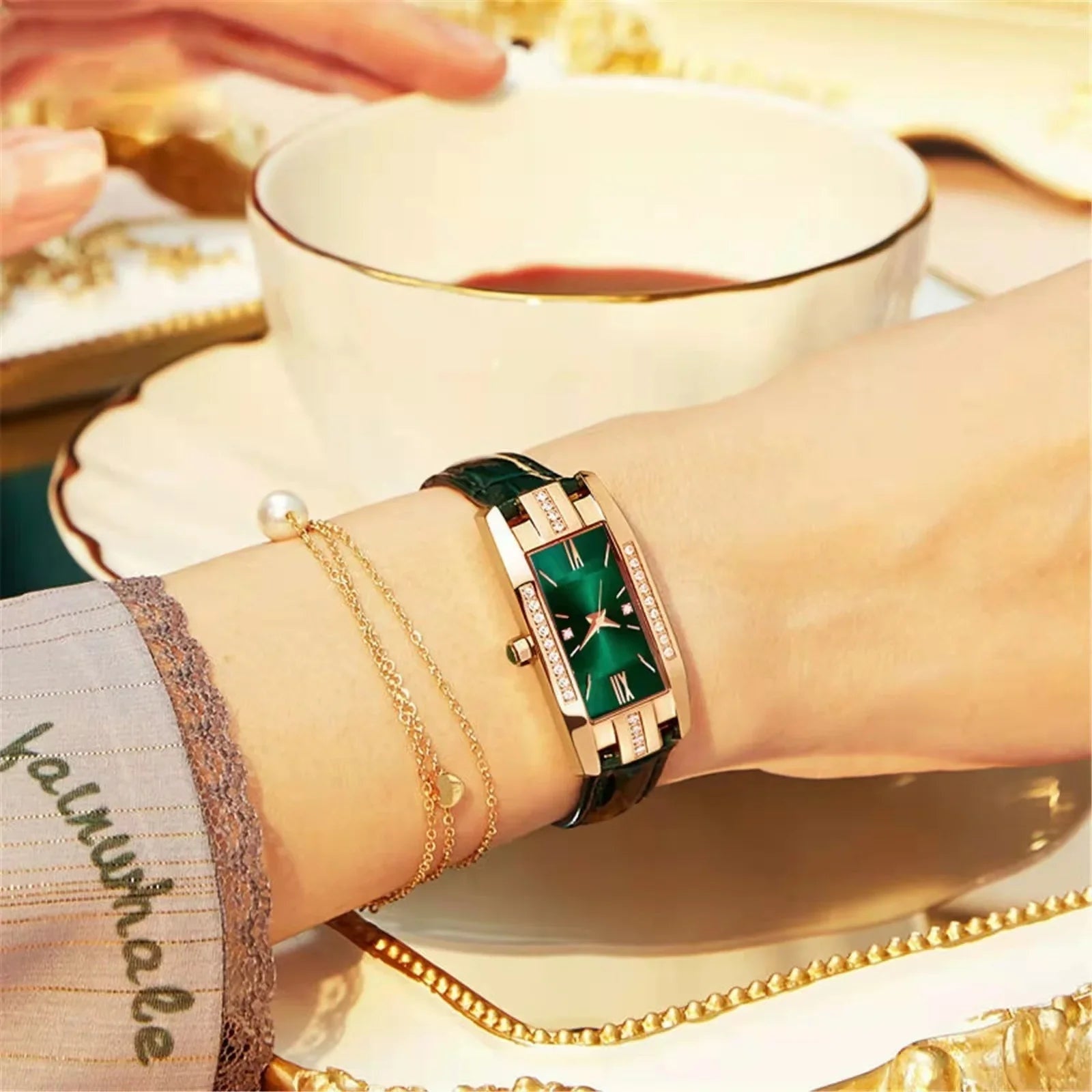 Close-up of a wrist wearing a green watch with a cup of tea in the background