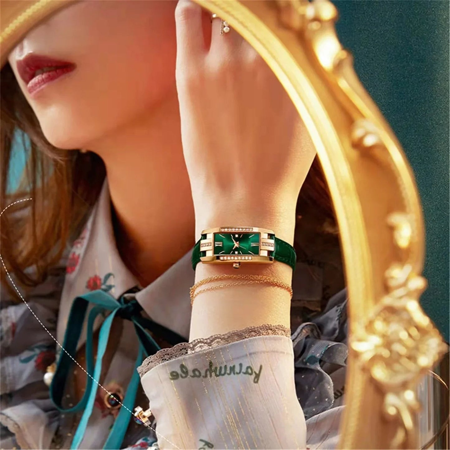 Woman wearing a green watch with a gold frame, standing in front of a decorative mirror.