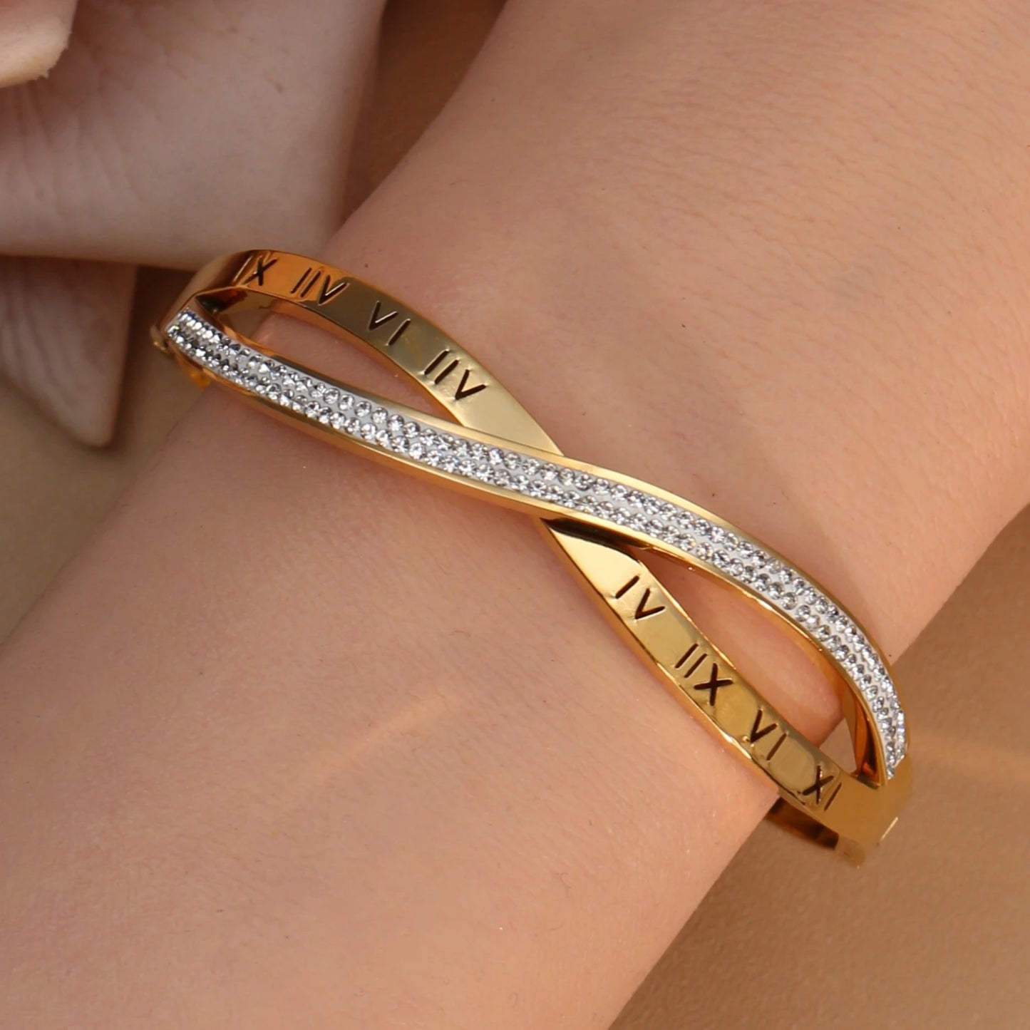 Gold stainless steel bangle with sparkling crystal accents on white background