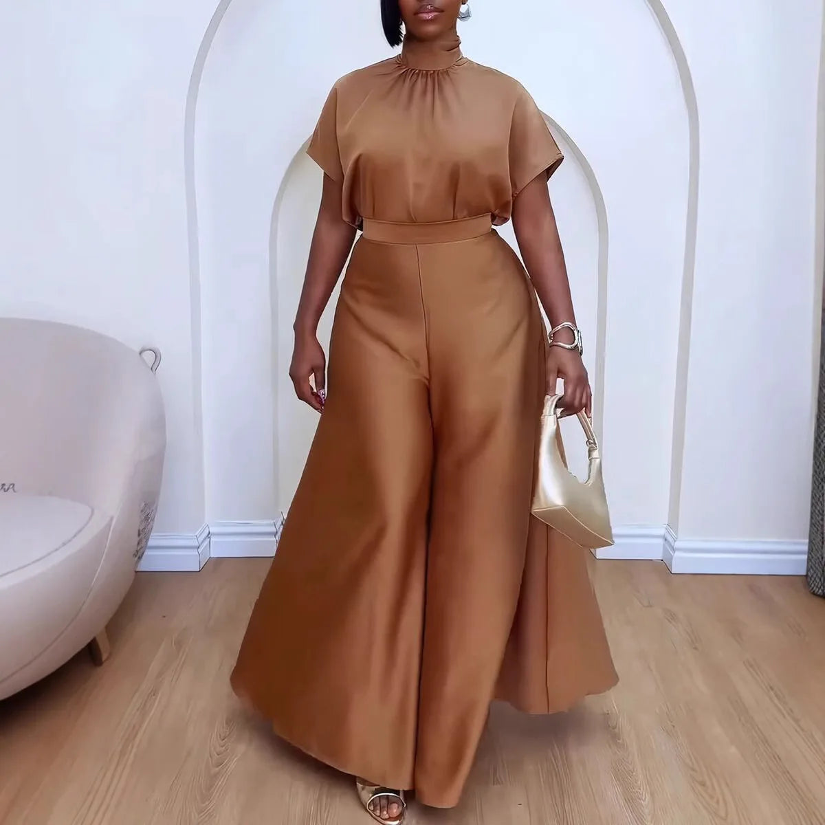 "Model wearing camel pantsuit with white handbag demonstrating professional styling"