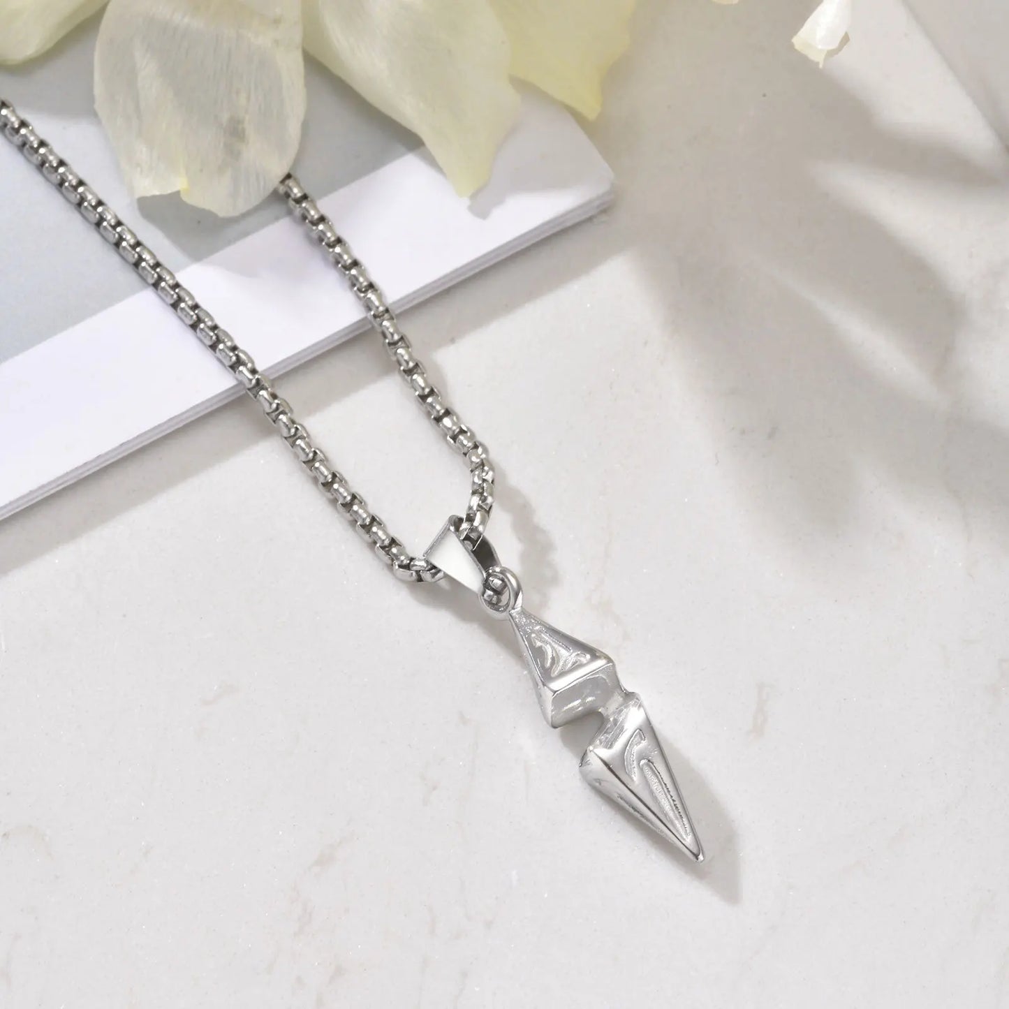 Men's arrow spike pendant necklace with full-length silver box chain on marble surface
