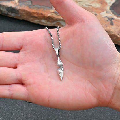 Silver arrow pendant necklace held in palm showing compact size on box chain