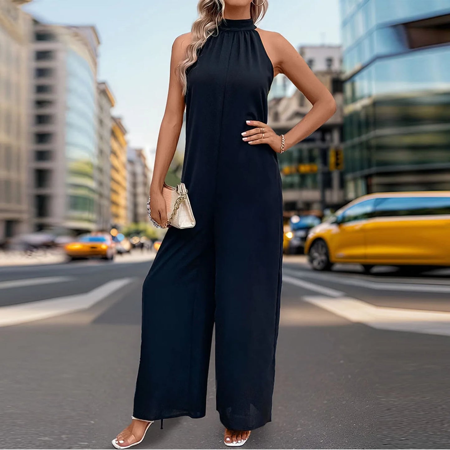 Woman wearing a wide-leg sleeveless jumpsuit in black with bow-tie back.